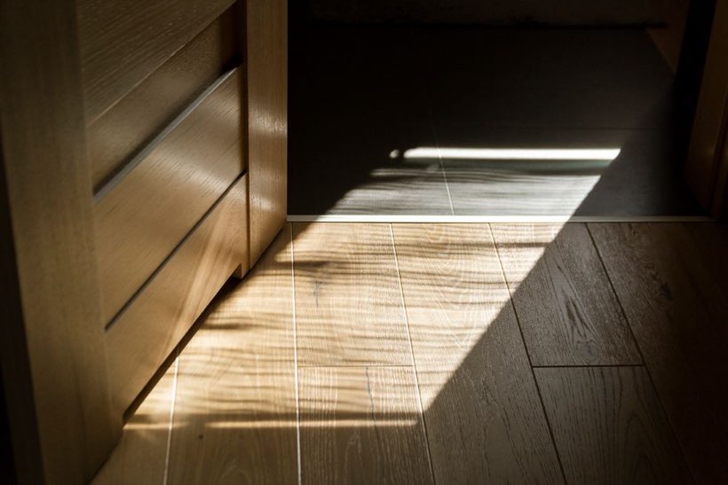 Sunlight raking across an oak floor in an Edmonton home, showing the sheen of a fresh top coat.
